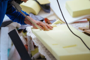 Mężczyzna pracujący przy obróbce mebli w fabryce, używający narzędzia do drewna