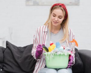 Kobieta czyści tapicerowaną sofę za pomocą specjalistycznych środków czyszczących