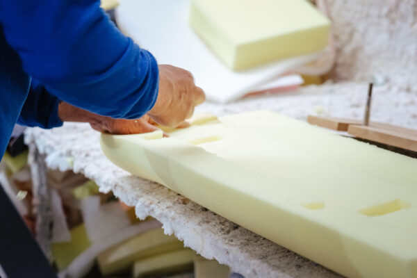 A vertical shot of a furniture maker shaping an upholstery foam